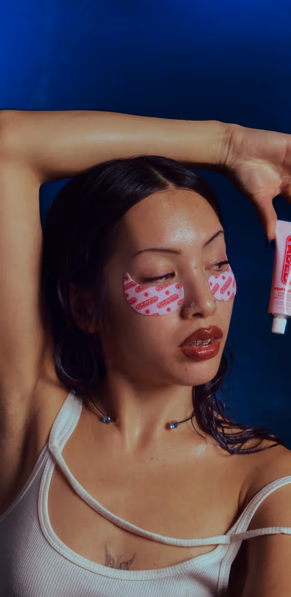A woman with pink hand wraps leans confidently on a boxing ring's ropes.